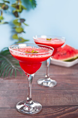 Watermelon refreshing summer frozen cocktail smoothie with watermelon slices and pieces on the background