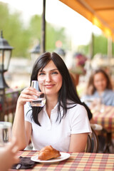 Smiling young women at cafe drinking white wine or water. Communication and friendship concept.