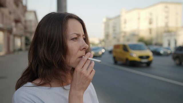 lonely woman is waiting someone on road junction and smoking cigarette