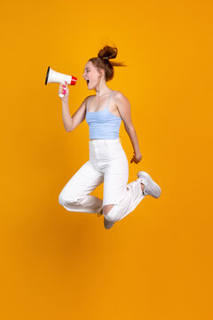 Vertical image of young cute girl jumping isolated on yellow studio background. Female fashion model in casual clothes. Concept of human emotions, natural beauty, youth