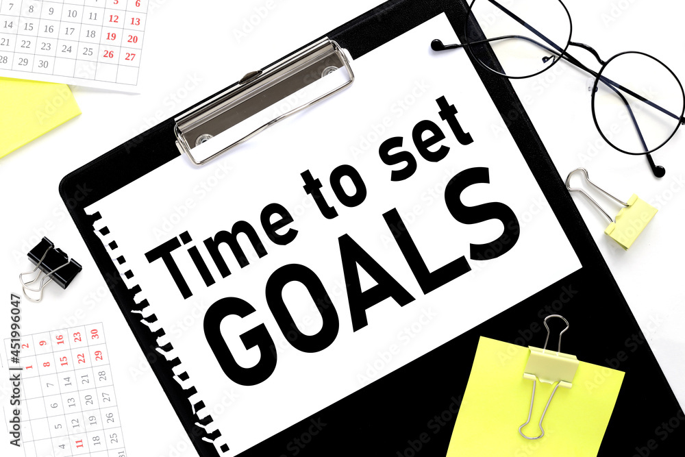 Poster time to set goals. text in notepad next to glasses on white background