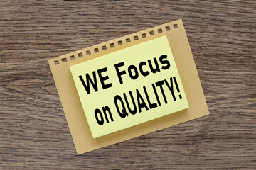 We focus on quality ! text on a wooden table, on a bright sticker