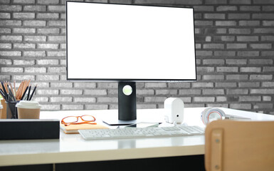 Mock up computer, headphone and office supplies on white desk with brick wall.