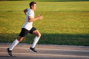 Fototapeta premium Man in sportive unifrom running on the track at daytime