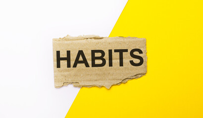 On a white and yellow background, brown torn cardboard with the text HABITS