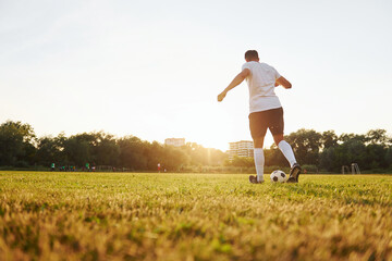 Runs with ball. Young soccer player have training on the sportive field