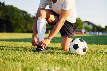 Ties laces. Young soccer player have training on the sportive field © standret