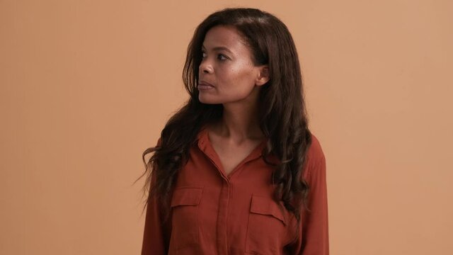 A brunette african american woman shaking hand doing hello gesture standing isolated over a beige background in the studio