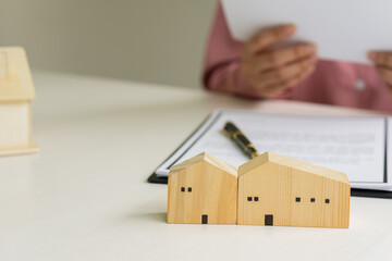 A home agent sitting at a desk in the office with a house plan with contract documents and a home buying idea, insurance or real estate loan idea calculator.