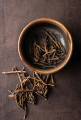 selective focus, natural green leaf tea. brewing in a clay bowl. vertical angle, macro. on a dark background. for menus and cafes