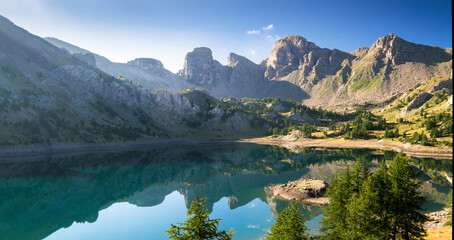 Allos lake in the morning during summer time, with mirror effect, mountains reflecting on the lake