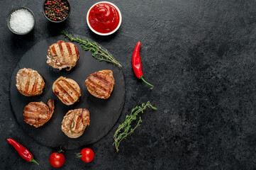 cooked grilled pork tenderloin medallions wrapped in bacon on stone background with copy space for your text	