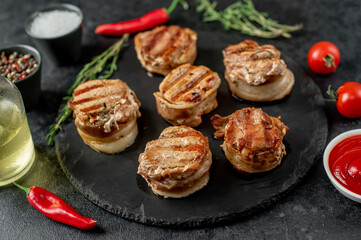 cooked grilled pork tenderloin medallions wrapped in bacon on stone background