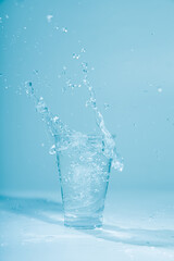 Ice cubes splashing into glass of water, isolated on white