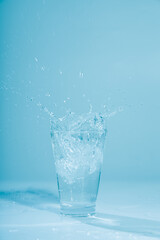 Ice cubes splashing into glass of water, isolated on white