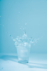 Ice cubes splashing into glass of water, isolated on white