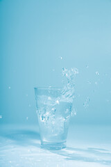 Ice cubes splashing into glass of water, isolated on white