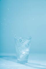 Ice cubes splashing into glass of water, isolated on white
