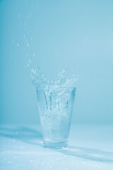 Ice cubes splashing into glass of water, isolated on white