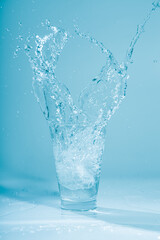 Ice cubes splashing into glass of water, isolated on white