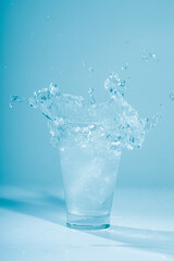 Ice cubes splashing into glass of water, isolated on white