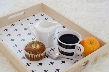 A breakfast in bed tray served with coffee, cupcakes and an organic orange