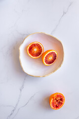 Halved blood oranges in white bowl