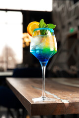 Layered alcoholic cocktail. Garnished with mint and a slice of orange.