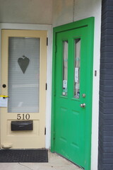  There are two doors in the outer hallway, one is a light yellow and the other is bright green.