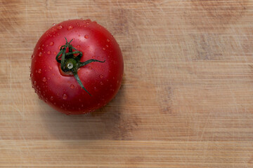 Juicy tomato with dewdrops on a wooden board