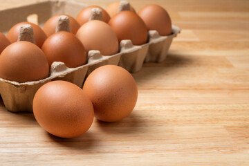 Chicken eggs in carton box on wooden table.