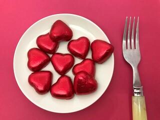 白いお皿に乗ったハート型のチョコレートとフォーク、バレンタイン・ホワイトデーイメージ
