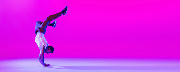 Flyer with dancing man, break dancer in action, motion in modern clothes isolated over bright magenta background at dance hall in neon light.
