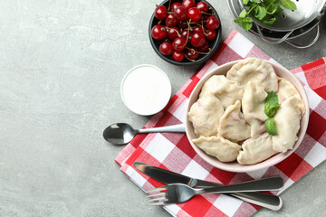 Concept of tasty food with pierogi with cherry on gray textured table