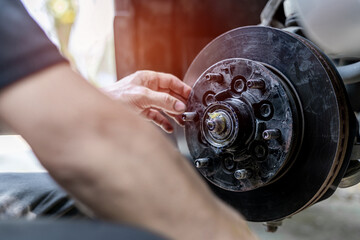 Fototapeta premium Close up disk of brake technician check drive shaft and grease in Bearing housing of wheel service checking the maintenance period of car for safety in travel