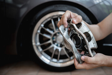 Car service run stop system concept : close up caliper brake of car in hand a man and wheel of car...