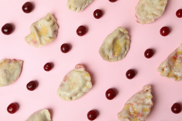Flat lay with pierogi with cherry on pink background