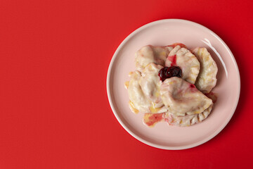 Plate with pierogi with cherry on red background