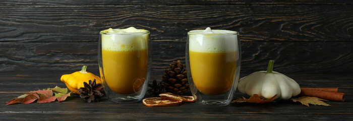 Glasses of pumpkin latte and ingredients on rustic wooden background