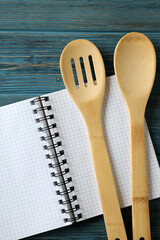 Empty recipe book and utensils on wooden table