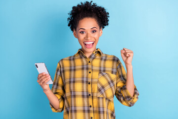 Photo portrait curly woman using cellphone gesturing like winner isolated pastel blue color background