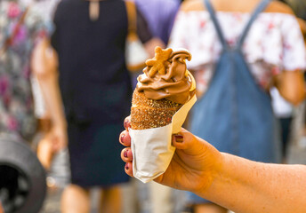 Person in Prague holding a trdelník chimney, which is a traditional cinnamon pastry filled with soft serve ice cream