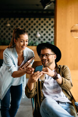 Young happy students have fun while using smartphone in cafe,