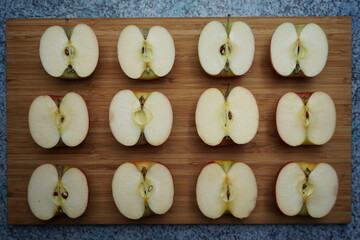 six halved apples lie on a wooden board