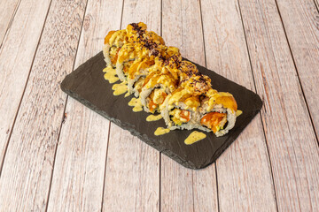 Uramaki tiger with prawns, cooked banana and sauces on a black slate plate