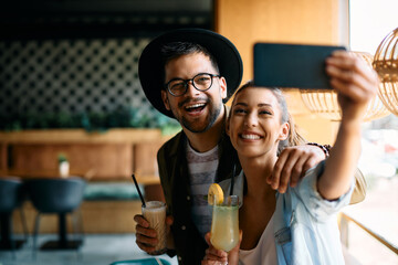 Young cheerful couple take selfie with smart phone and have fun in cafe.