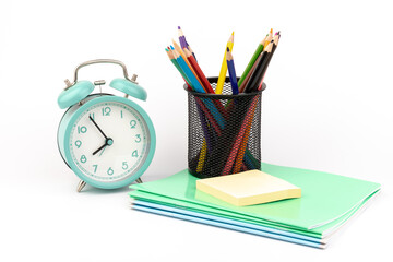 Fototapeta premium School items. Alarm clock, notebooks, pencils for drawing on a white background. Concept of education, back to school, creativity and learning. Copy space.