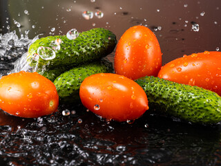 tomatoes and cucumbers on a dark background with splashes of water