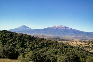 El volcán Popocatépetl y Iztaccihuatl vistos desde un bosque alejado.