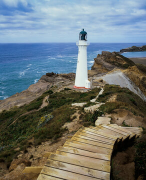 Set of wooden steps leading down to Castle Point Lighthouse on rocky cliff edge and blue pacific ocean below